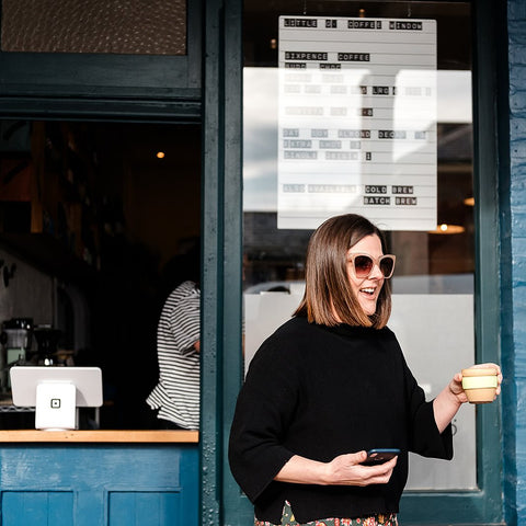 Lady holding coffee as she walks away from service window