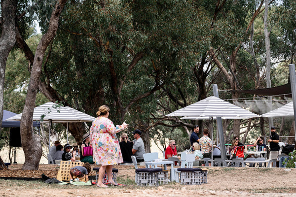 People gathered under umbrellas and trees