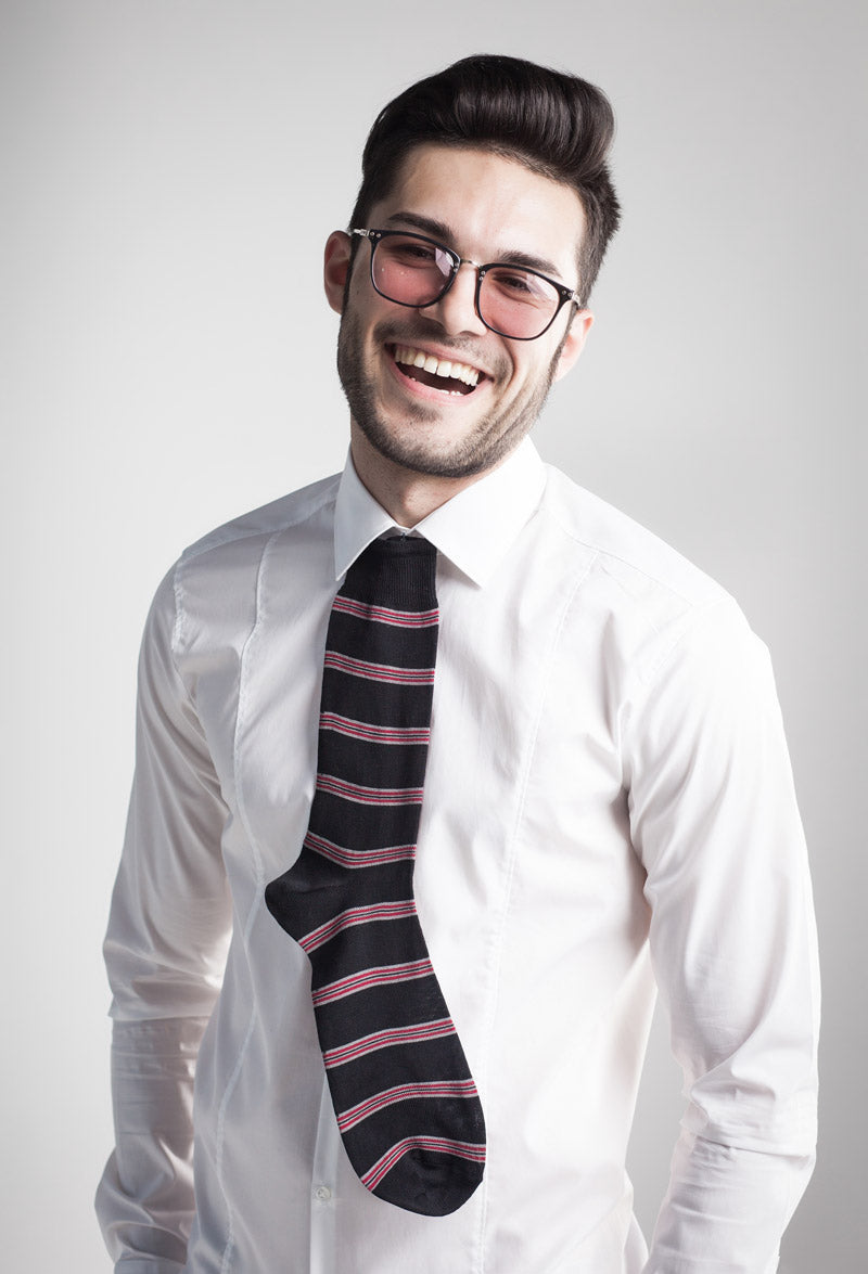 A man in a white business shirt wears a sock for a tie and a pair of sunglasses