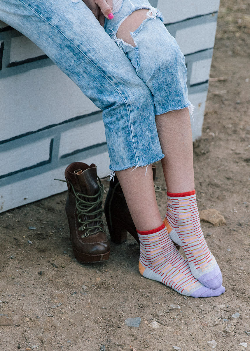 Cute striped ankle socks are worn with ripped jeans and stand beside a pair of lace-up high-heeled boots