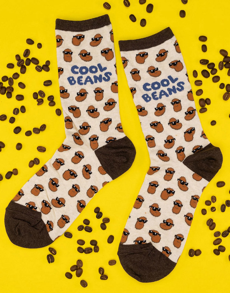 Cool beans socks for women with beans wearing sunglasses lay flat surrounded by coffee beans