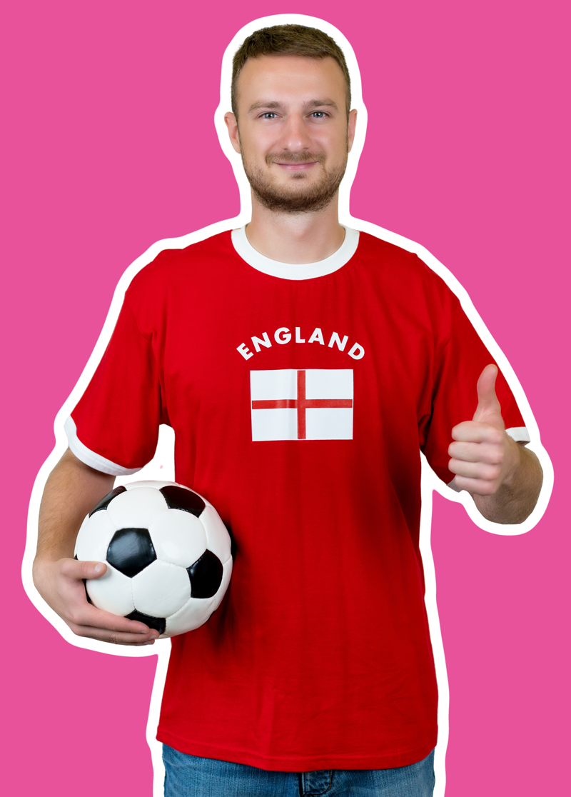 A man in a soccer shirt holds a soccer ball and gives a thumbs-up