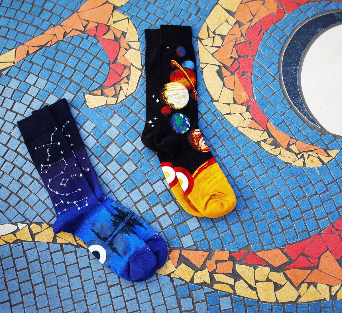 Socks with stars and planets placed on a mosaic of space