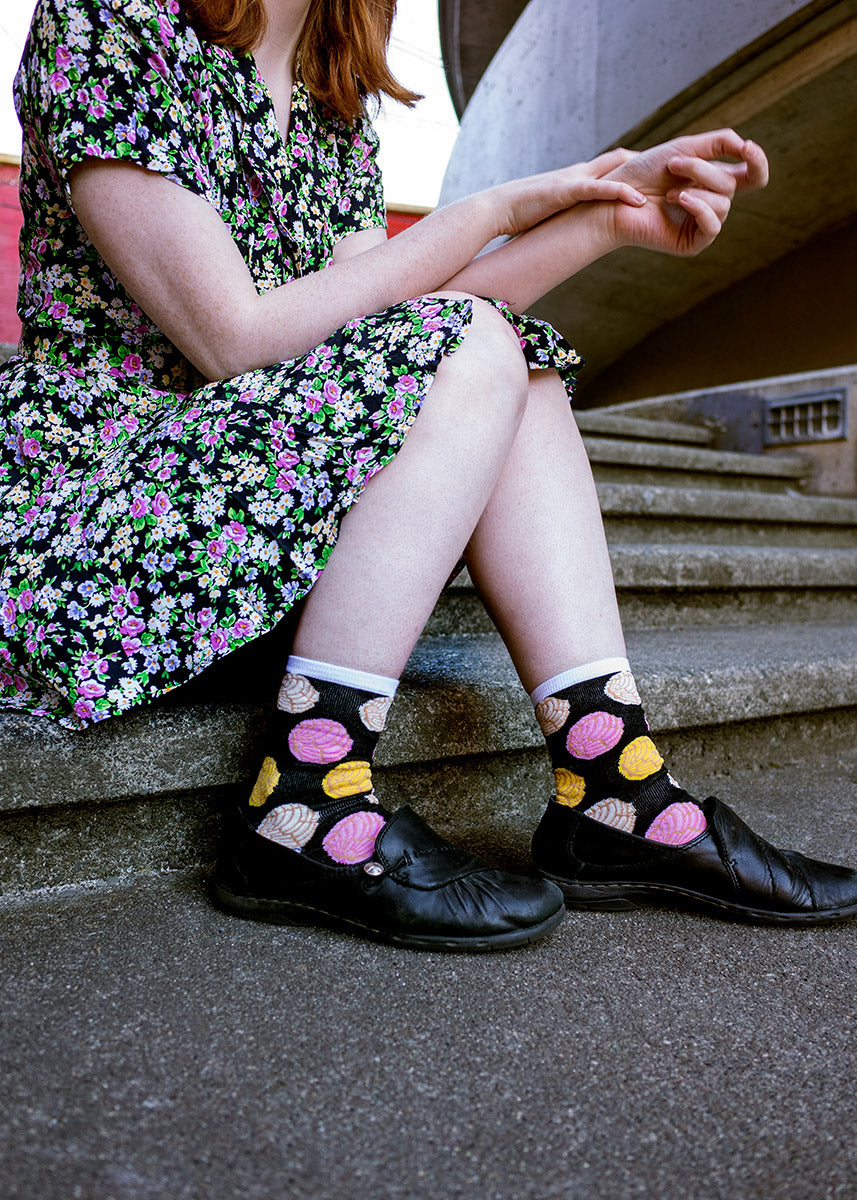 Andrea wears pan dulce socks with black shoes and a floral print dress