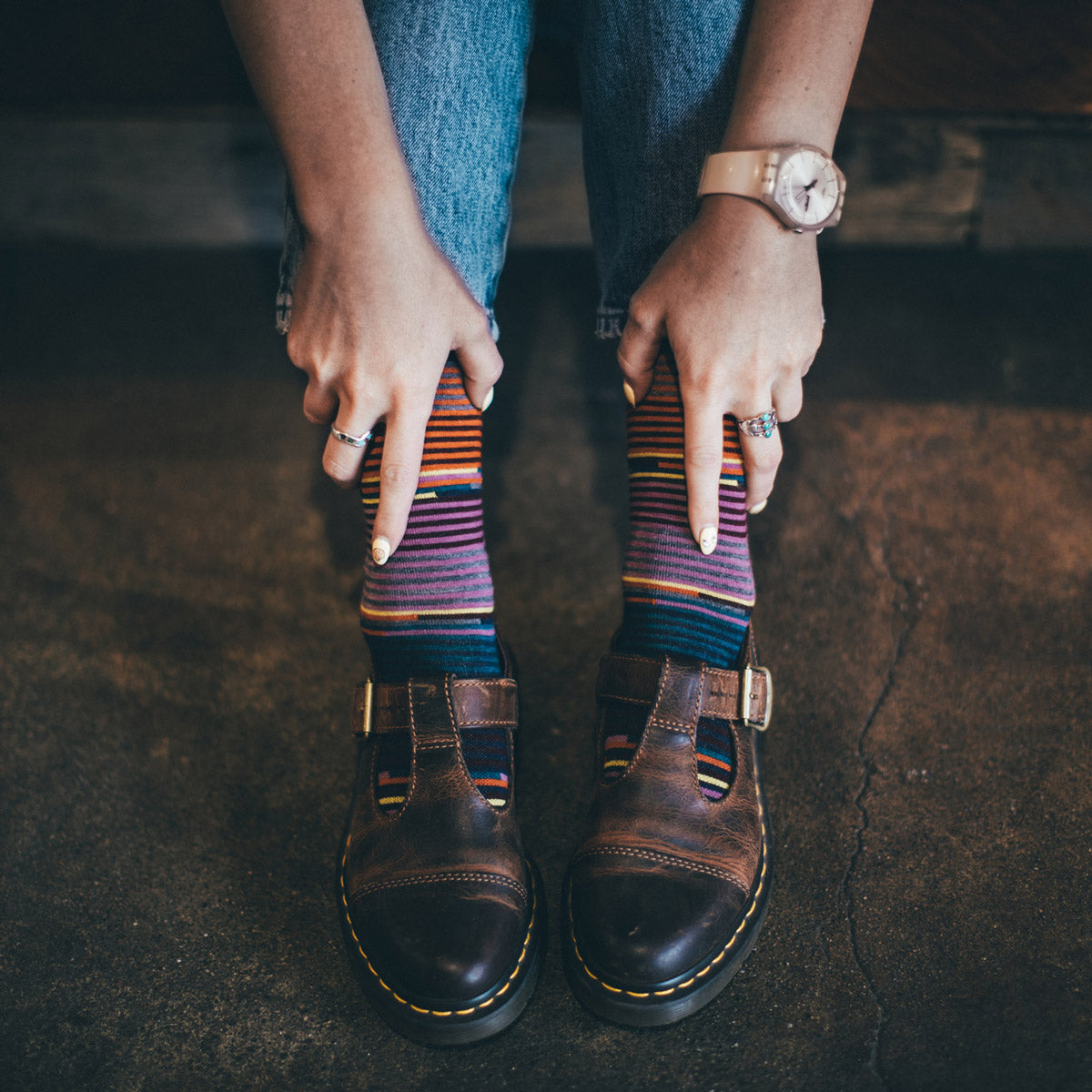 A person shows off their striped merino wool socks worn with monk strap shoes and jeans.