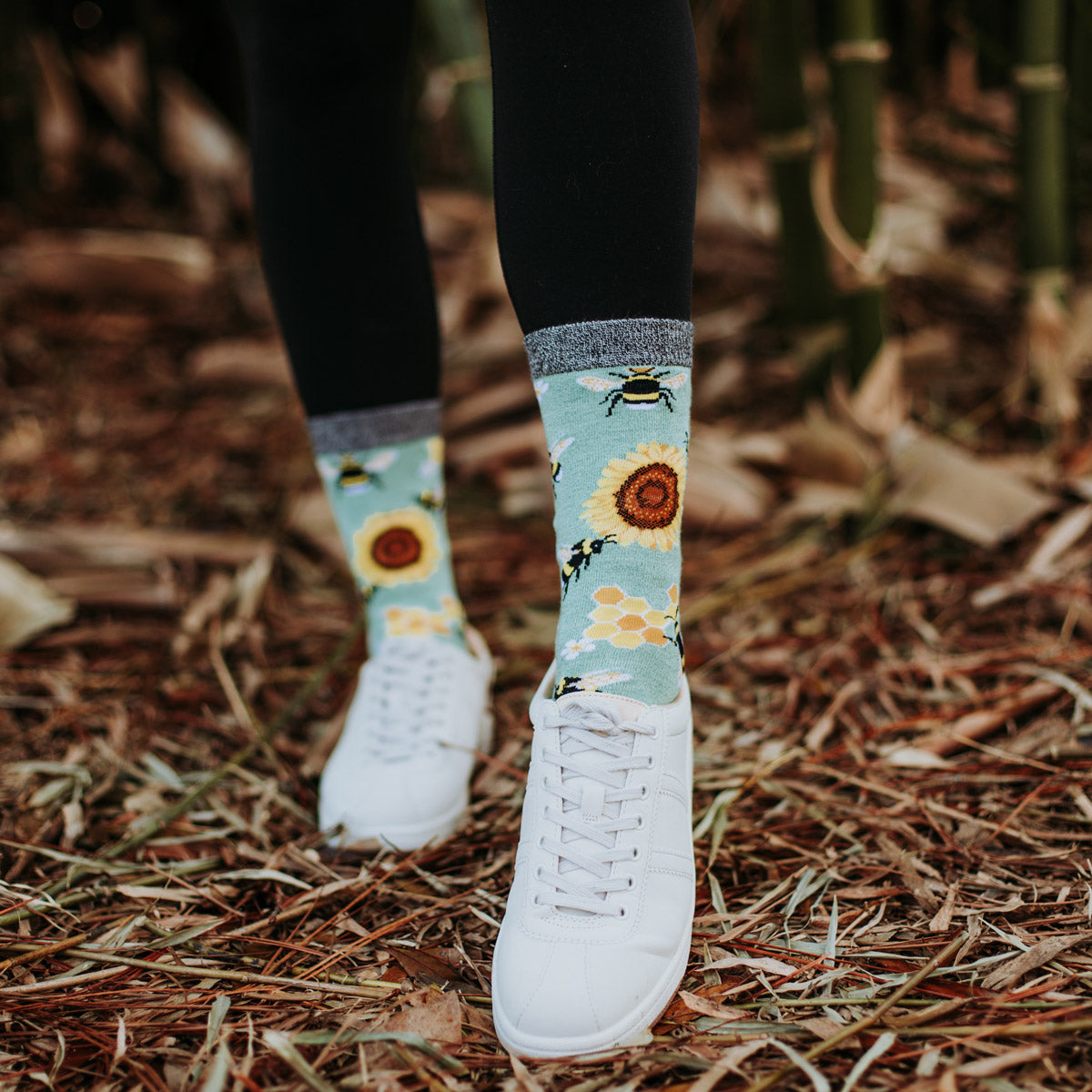 Bee and sunflower socks worn with white shoes and pulled over black leggings for an athleisure look