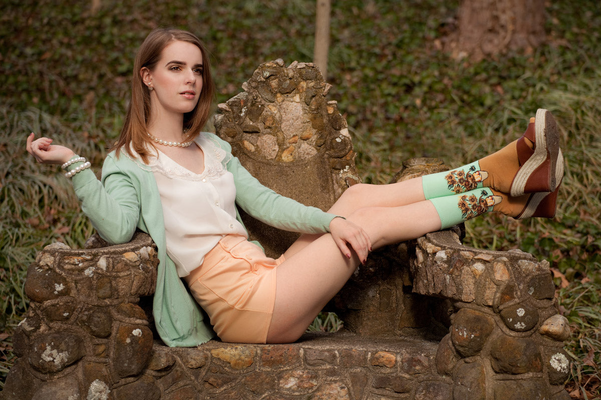 A model shows a preppy sock look with sunflower socks and platform shoes worn with pastel clothing and pearl jewelry 