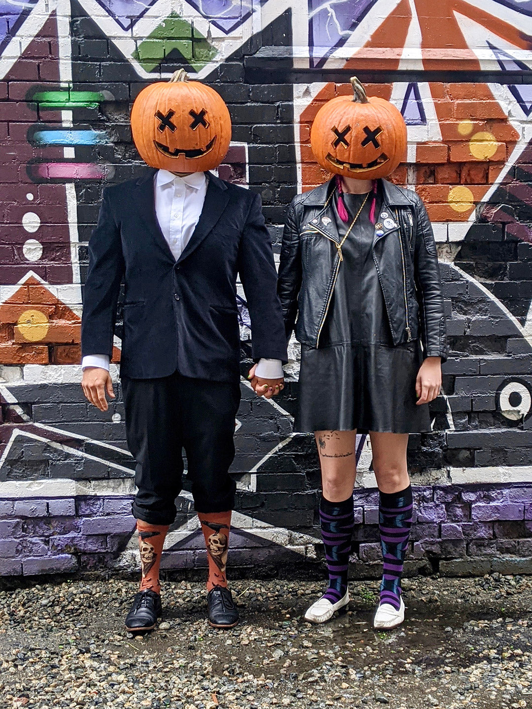 A couple with jack-o-lantern heads shows off Halloween fashions with fun Halloween socks 