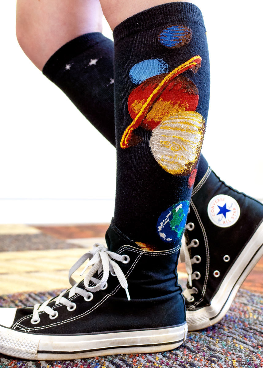 Solar system knee socks are worn with black converse shoes.