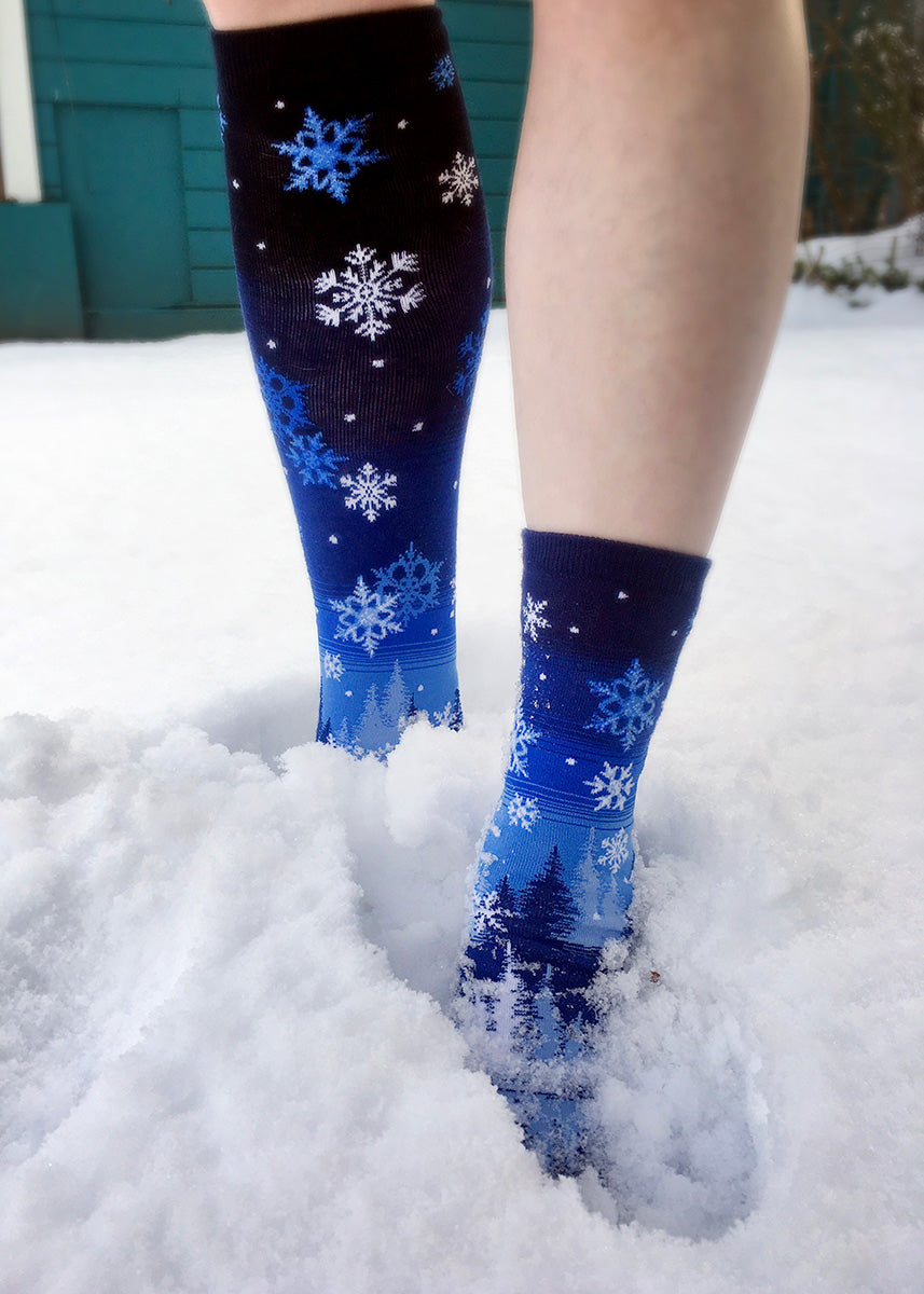 A person in snowflake socks steps through the snow.