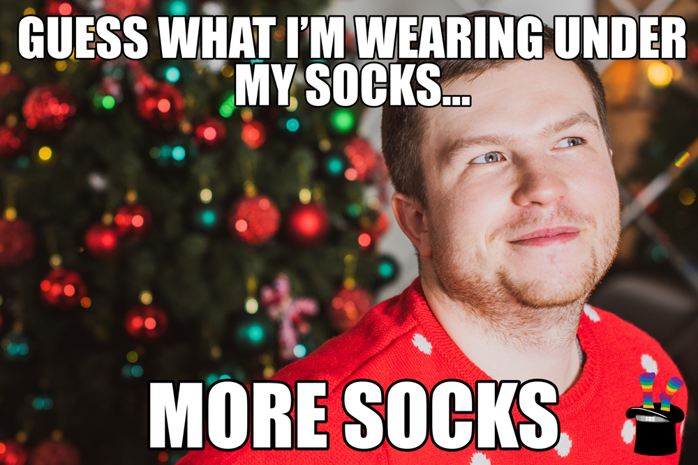 Text reads: Guess what I'm wearing under my socks? More Socks. Image shows a man smiling in front of a Christmas tree.