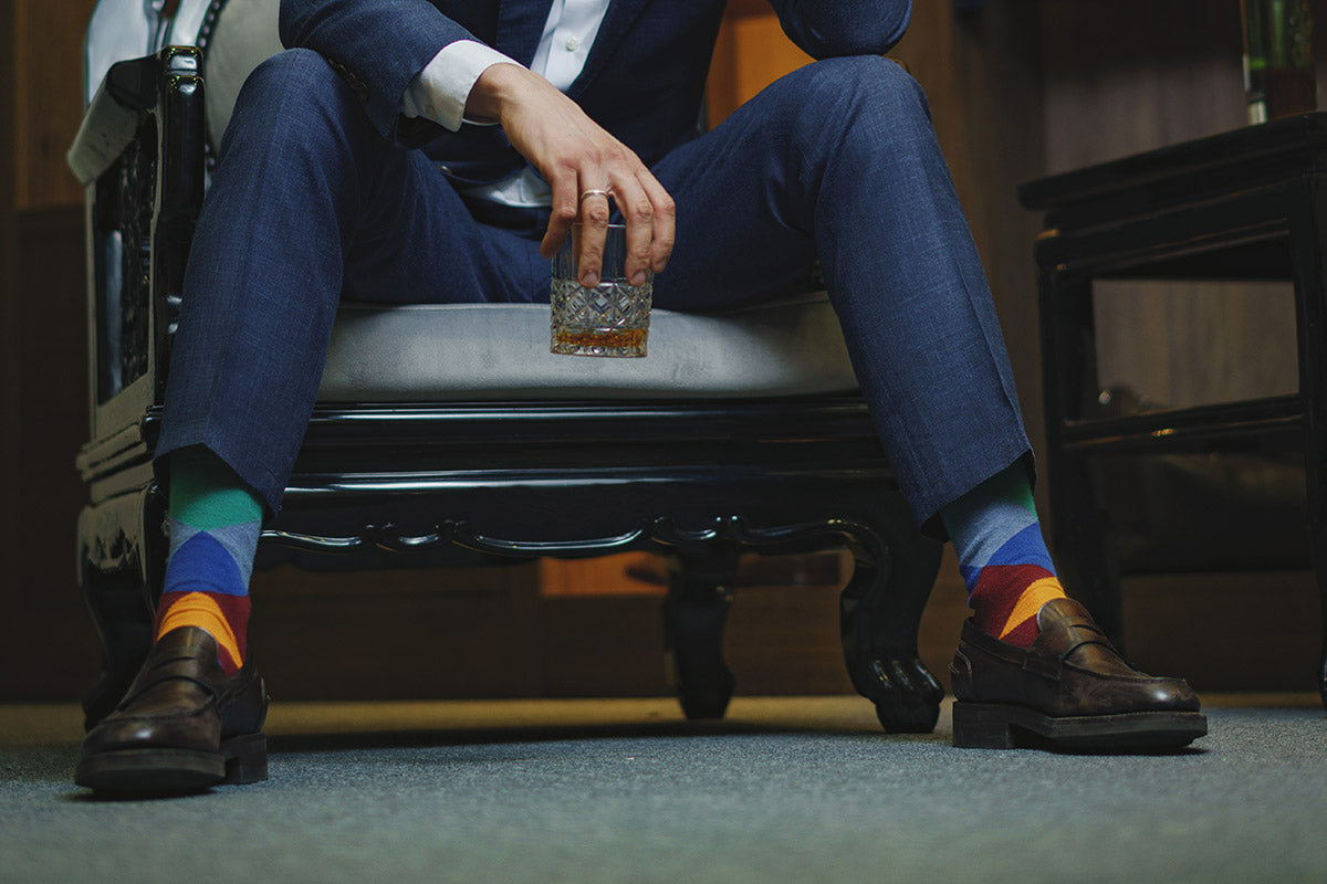 A man wears colorful geometric dress socks with monk strap dress shoes