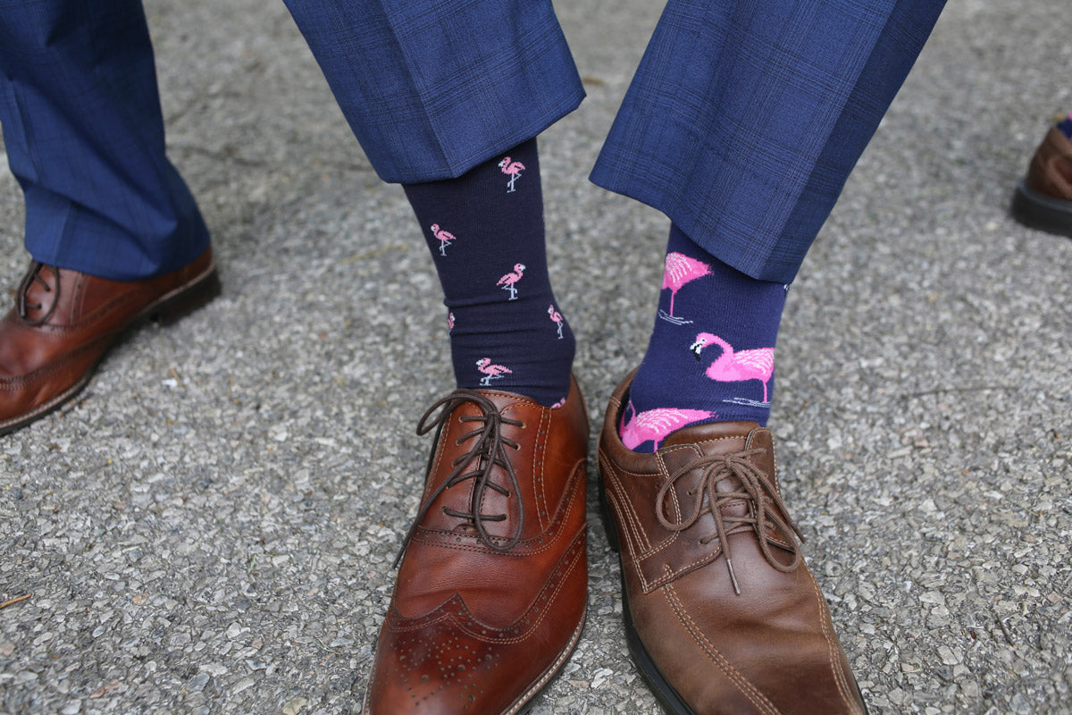 Two men show of flamingo socks worn with blue suits and brown dress shoes