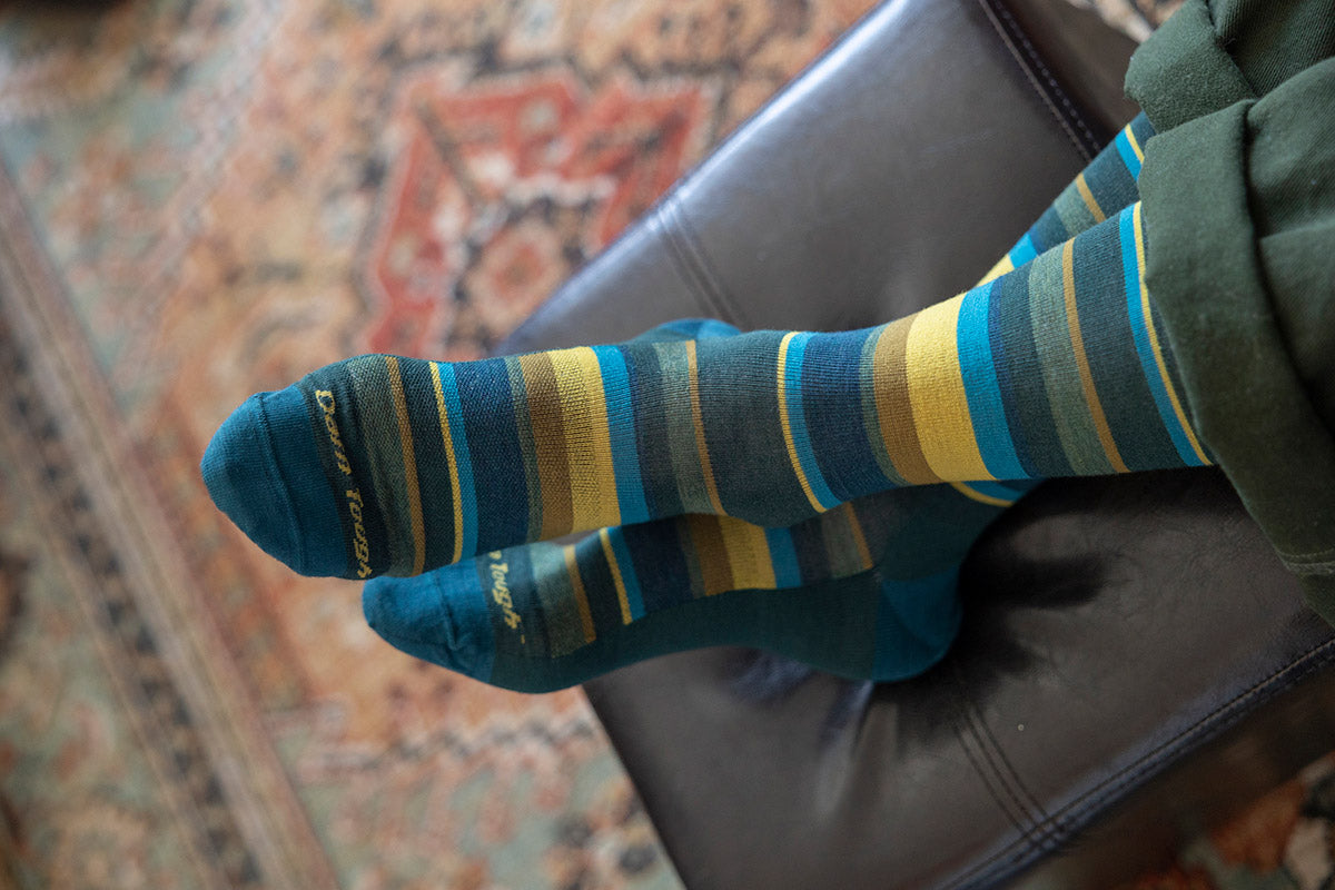 A man wears Darn Tough merino wool socks with teal stripes