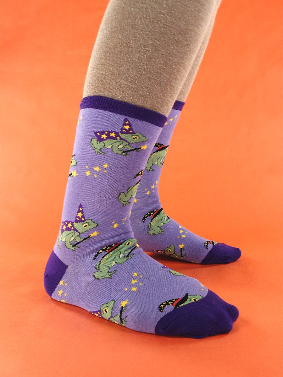 Purple socks with a motif of wizard frogs, worn by a model over tan tights.