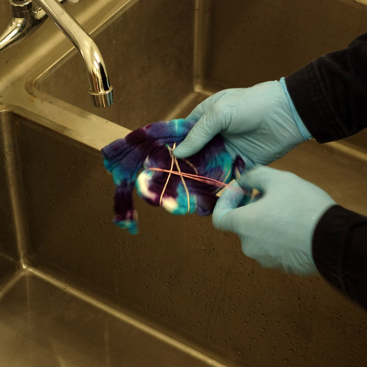 Removing rubber bands from tie-dyed socks before rinsing them in the sink