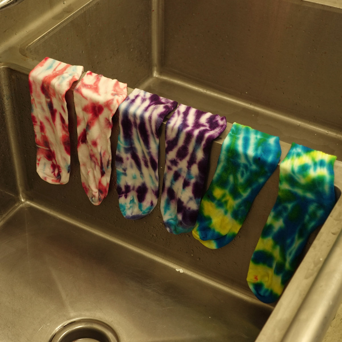 Tie-dyed socks that have been rinsed and are ready to wash.