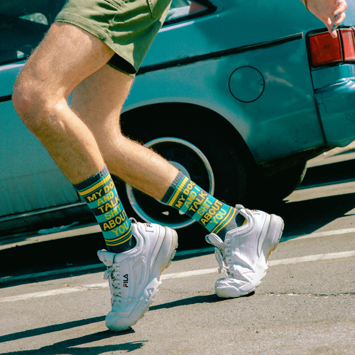 A man runs in shorts, sneakers and socks that say "My Dog and I Talk Shit About You."