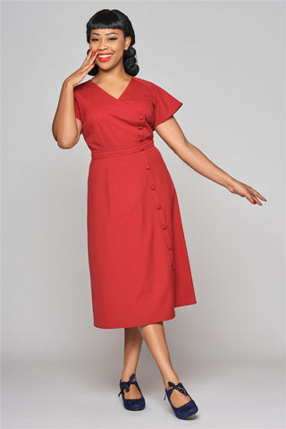 Glamorous woman in a red dress with button down front smiling mid-stride