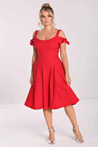 Elegant blonde woman standing in a 50s style red fit and flare dress with off the shoulder straps