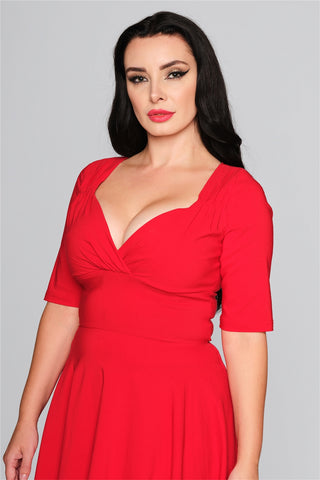 Woman with black hair and red lipstick in a 50s style red fit and flare dress
