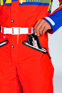 A person in a red jumpsuit putting a phone in their pocket.