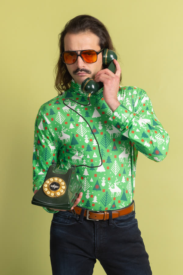 A man in a green Christmas shirt holding a telephone, wearing sunglasses.