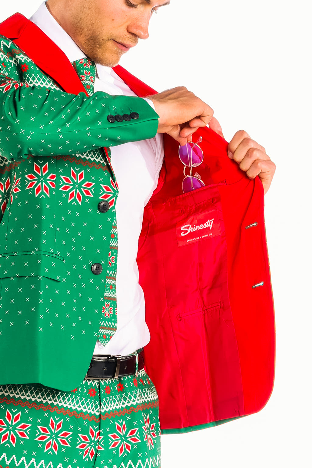 A person in The Kris Kringle | Green Fair Isle Christmas Suit holding a red jacket and wearing festive attire.