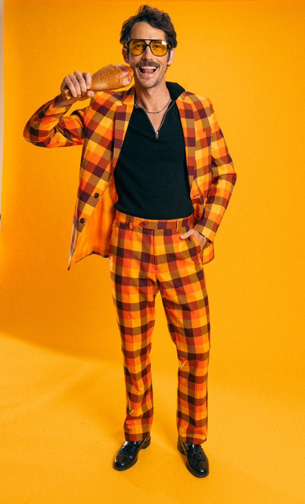 That 70s Suit | Thanksgiving Plaid Suit, a man in a unique plaid outfit holding a turkey leg.