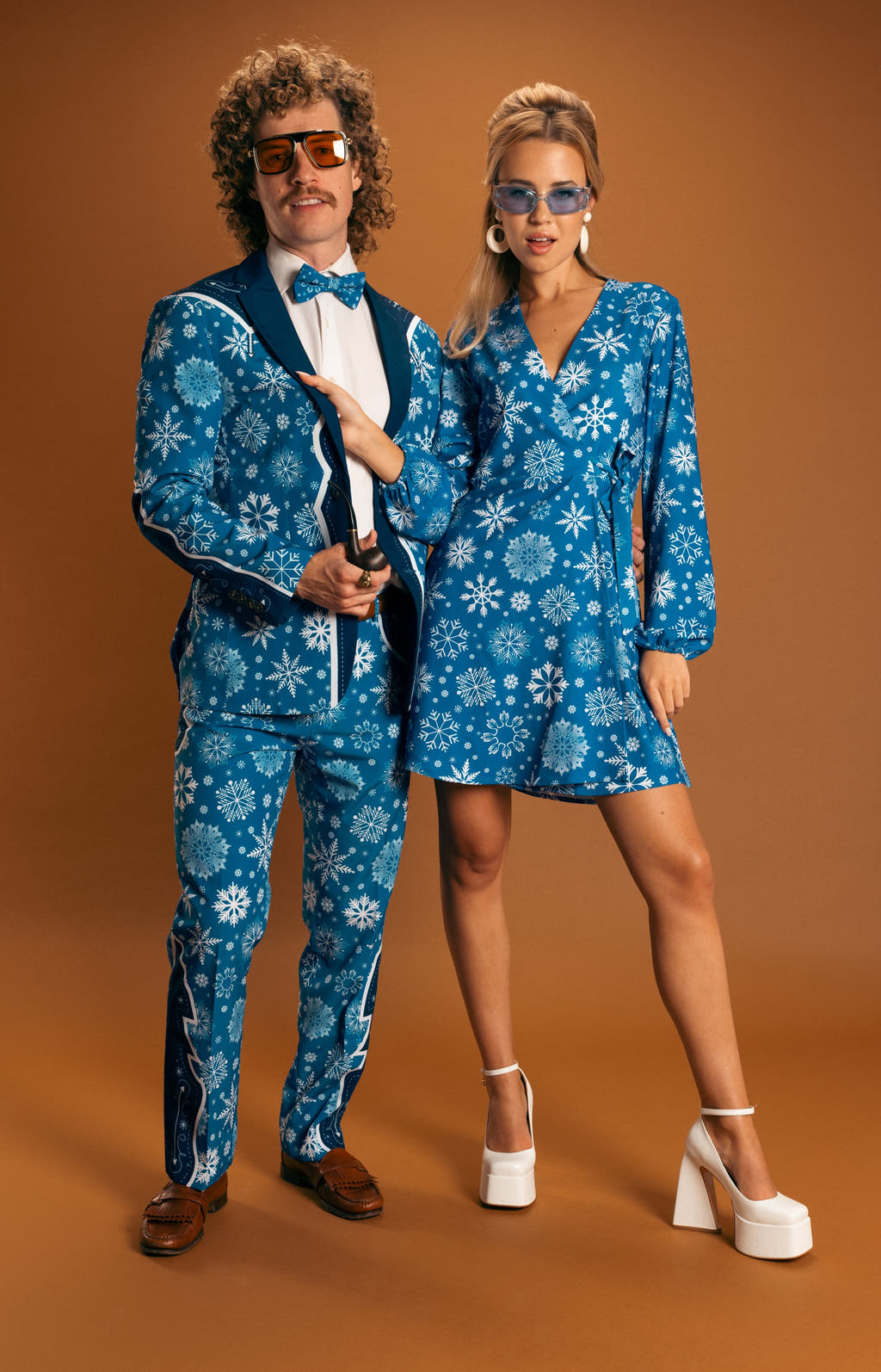 A man and woman in unique holiday attire, showcasing individuality with The Ice Never Melts | Blue Snowflake Christmas Suit.