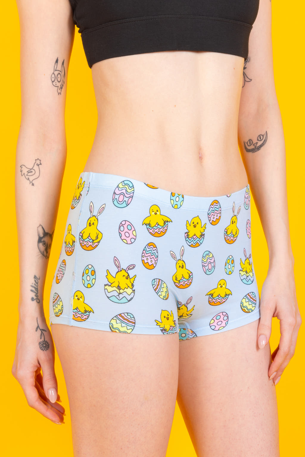 A person wearing Easter-themed boyshort underwear with cartoon chicks and eggs.