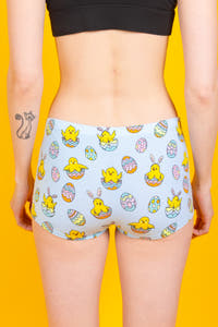 A person wearing cartoon-themed boyshort underwear with playful Easter chicks and eggs.