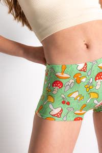 A woman wears The Trip Advisor Mushroom Modal Boyshort Underwear. Shinesty's eccentric collection brings bold, retro vibes to life with outlandish clothing choices.