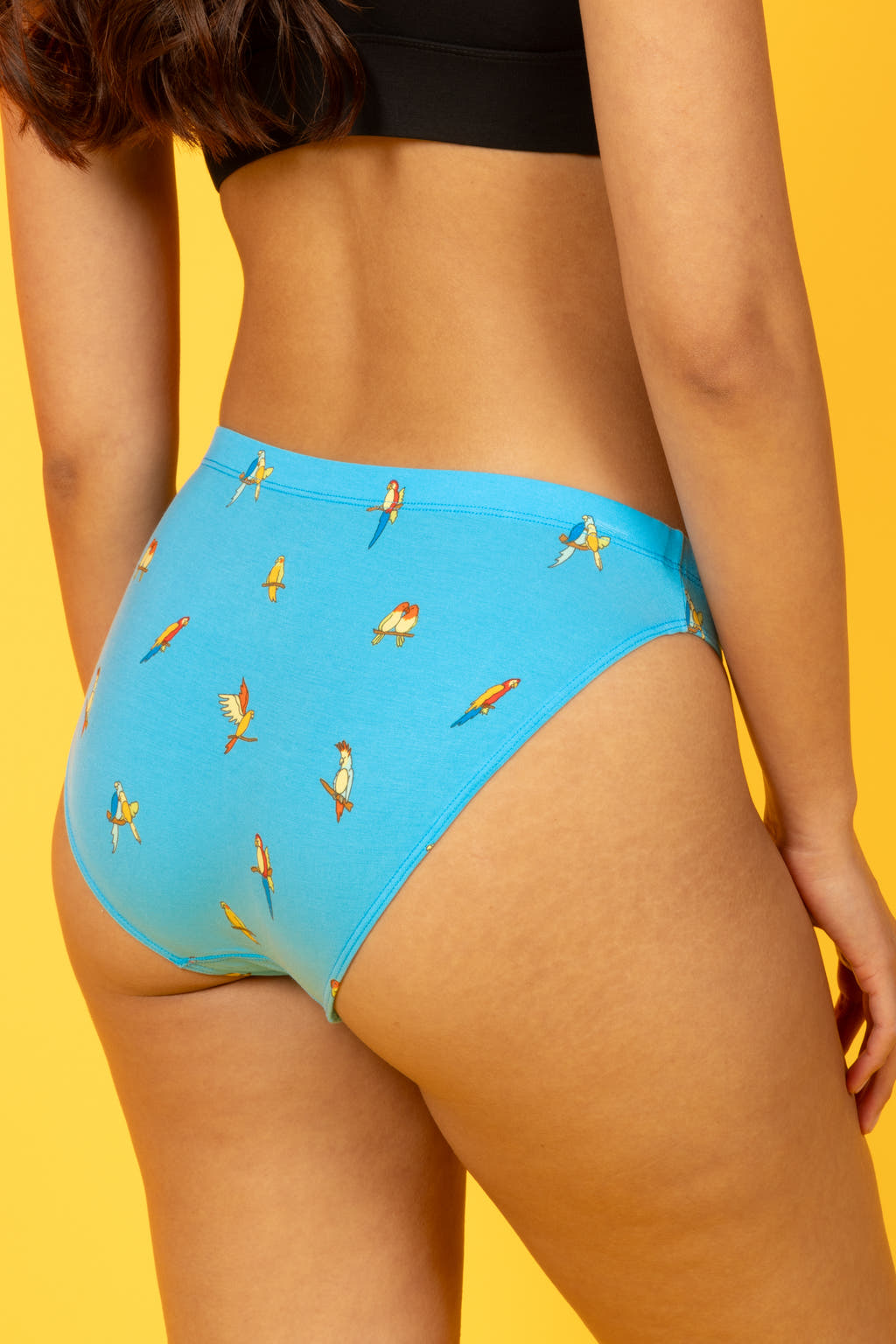 A woman wears The Tweet Yourself Parrot Modal Bikini Underwear, pondering bird sounds. Shinesty's quirky style shines through.