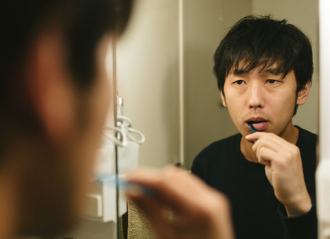 鏡を見ながら歯を磨く男性