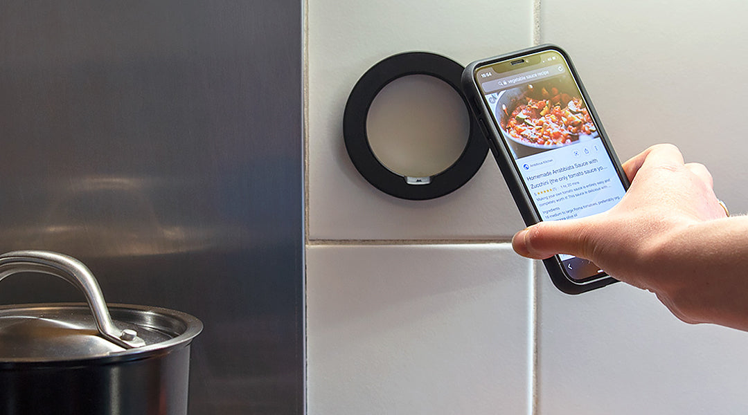 Person placing iPhone onto a magnetic phone mount in the kitchen above a saucepot