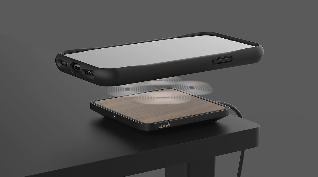 iPhone floating above a Mous AutoAlign+™ wireless charger on a table