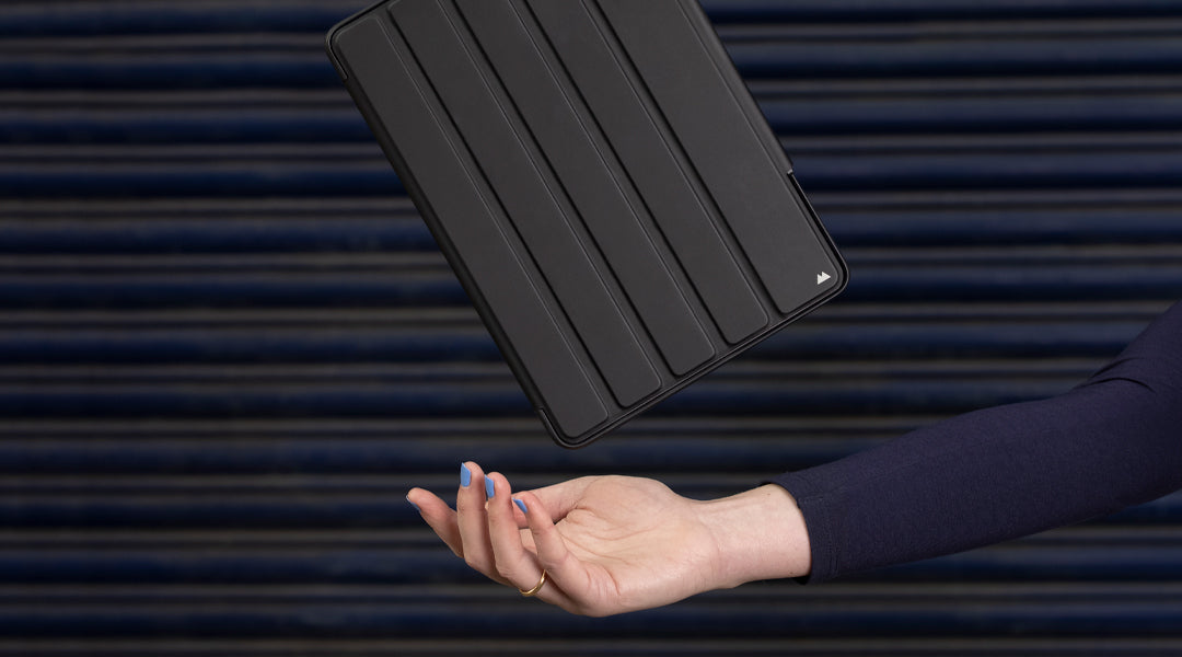 Black Mous iPad cases above woman’s hand in front of corrugated metal