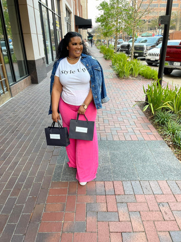 Morgan B. holding shopping bags while wearing a graphic t-shirt and pink overflow pants