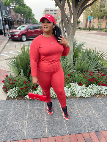 Morgan B. wearing a solid rust orange two piece set with a red handbag and red and black Jordan one's sneakers