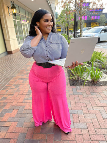 Morgan B. holding a laptop while wearing a black and white stripe button down shirt with pink overflow pants 
