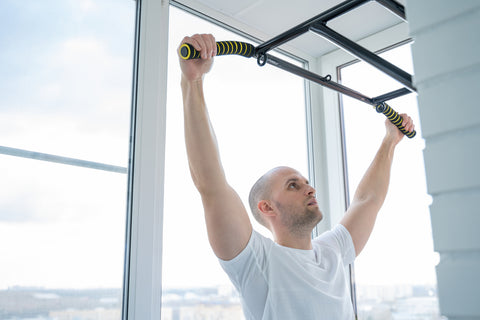 man using a pull up bar in his home gym