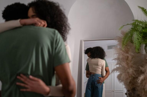 Diverse couple hugs in front of mirror