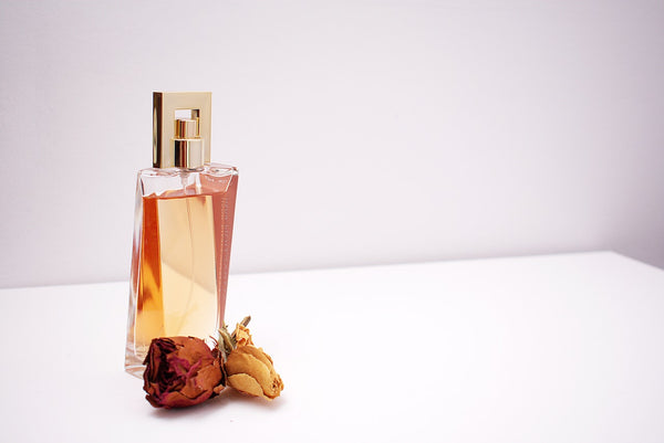 Clear glass perfume bottle with amber liquid and dried flowers