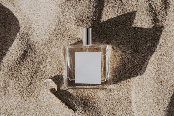 Clear perfume bottle in sand