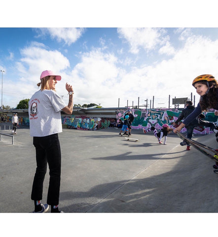 Amber Clyde teaching skateboarding to girls at park