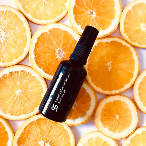 Black Bottle of Kakadu Plum Vitamin C Serum lying on slices of oranges