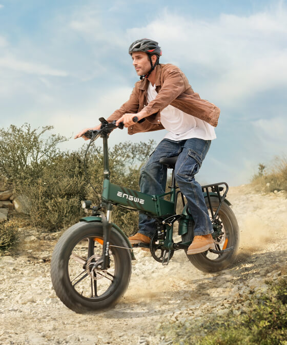 a man wearing a bike helmet rides an engwe engine pro 2.0 on the sand