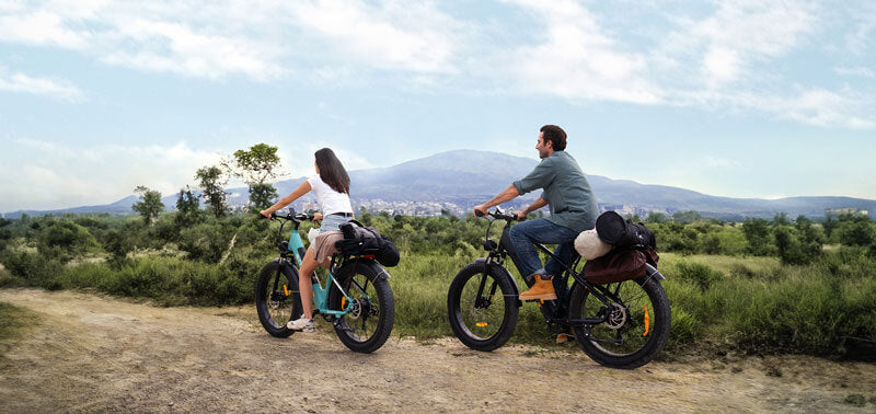 a man and a woman riding 2 fat tire electric bikes - engwe e26