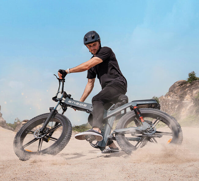 a man rides the engwe x26 folding fat tire electric bike on the sand